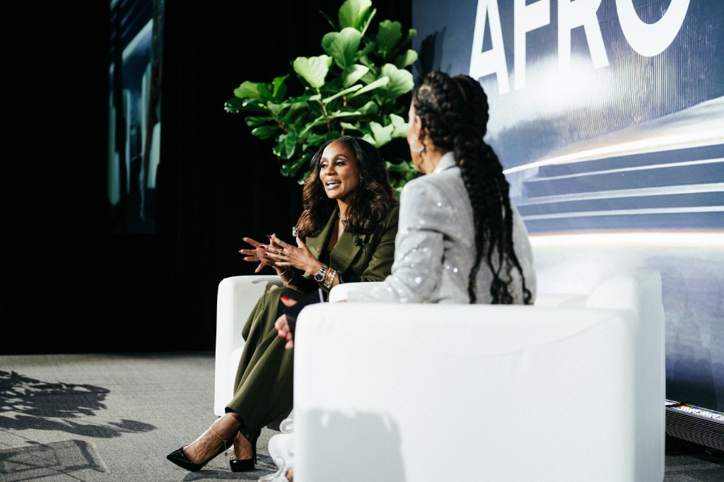 Speakers seated in white chairs on stage at AfroTech